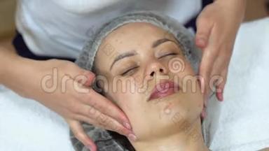 按摩治疗师正在对客户`面部进行手动按摩。 面部美容治疗.. 水疗面部按摩